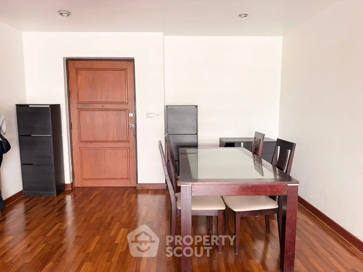 Spacious dining area with wooden flooring and elegant furniture in modern apartment.