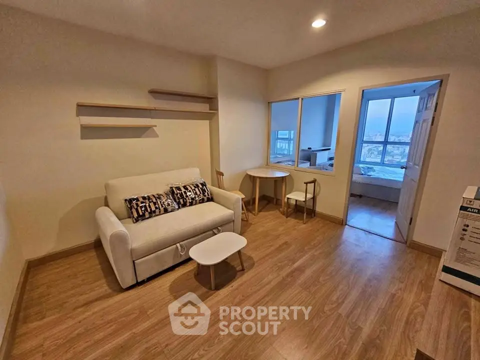 Cozy living room with wooden flooring and modern furniture in a well-lit apartment.