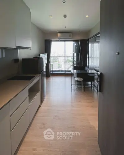 Modern open-layout kitchen and living room with balcony view in a stylish apartment.