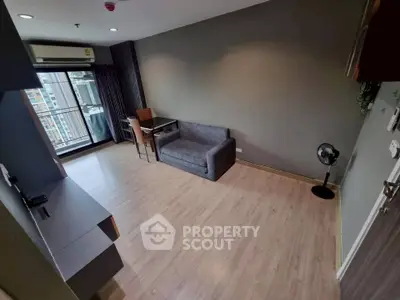 Modern living room with city view, featuring sleek furniture and wooden flooring.