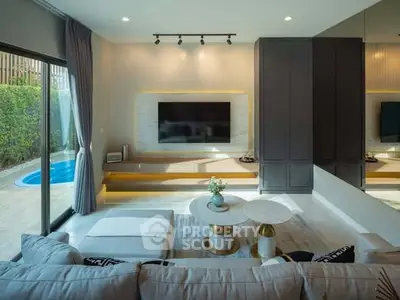 Modern living room with pool view, stylish furniture, and large TV setup.