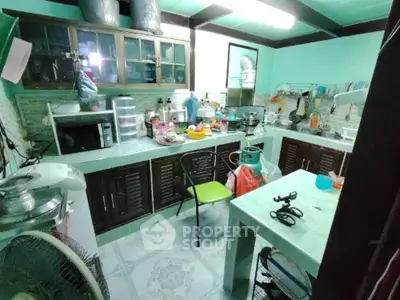Spacious kitchen with ample storage, tiled floors, and a large central table, ideal for family gatherings and culinary enthusiasts.