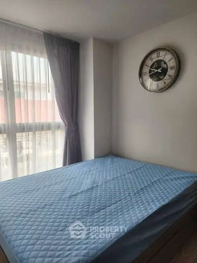 Cozy bedroom with large window and stylish wall clock, perfect for natural light lovers.