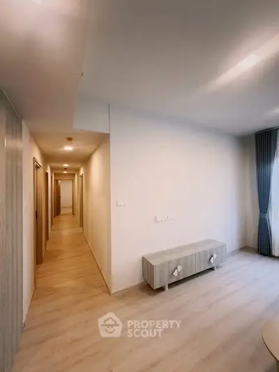 Spacious hallway leading to a bright living area with modern decor and natural light.