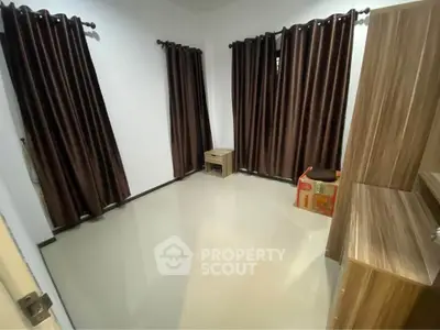 Spacious unfurnished room with elegant dark curtains and sleek wooden furniture.