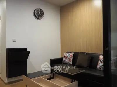 Modern living room with sleek black sofa and stylish wall clock
