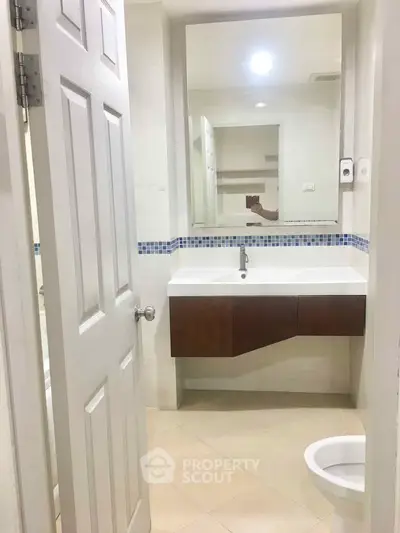 Modern bathroom with sleek sink and large mirror in a bright, minimalist design.