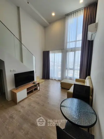 Spacious modern living room with high ceilings and large windows offering stunning city views.