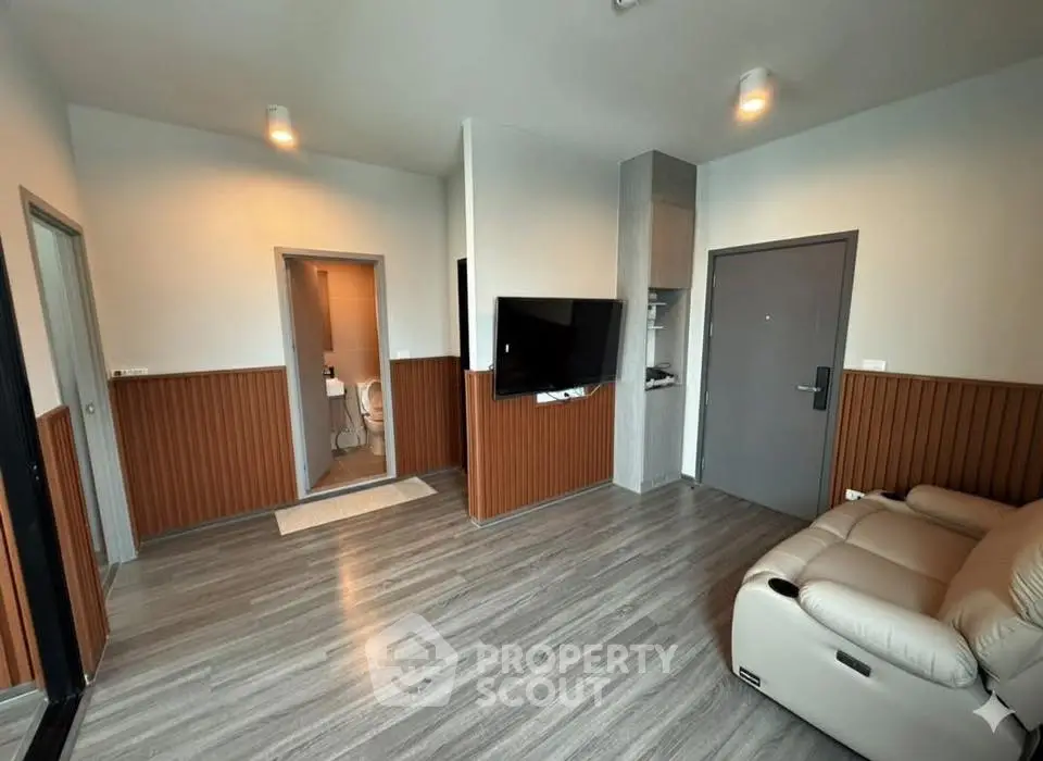 Modern living room with sleek flooring and wall-mounted TV, featuring cozy seating and stylish lighting.