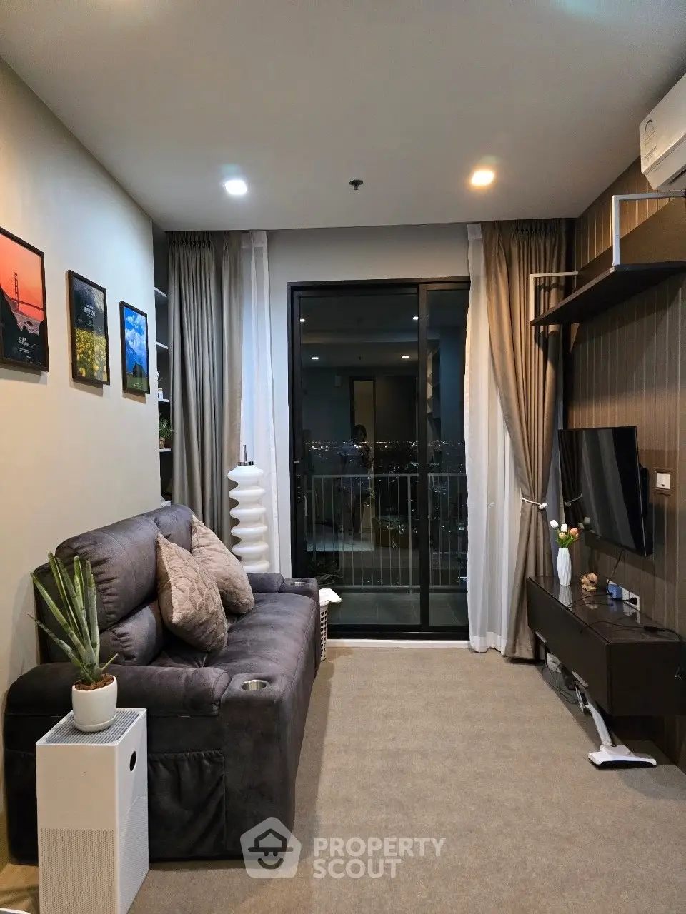 Modern living room with cozy sofa, stylish decor, and balcony view in a high-rise apartment.