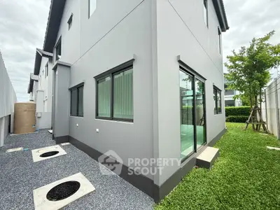 Modern gray exterior of a two-story house with lush green lawn and sleek windows.