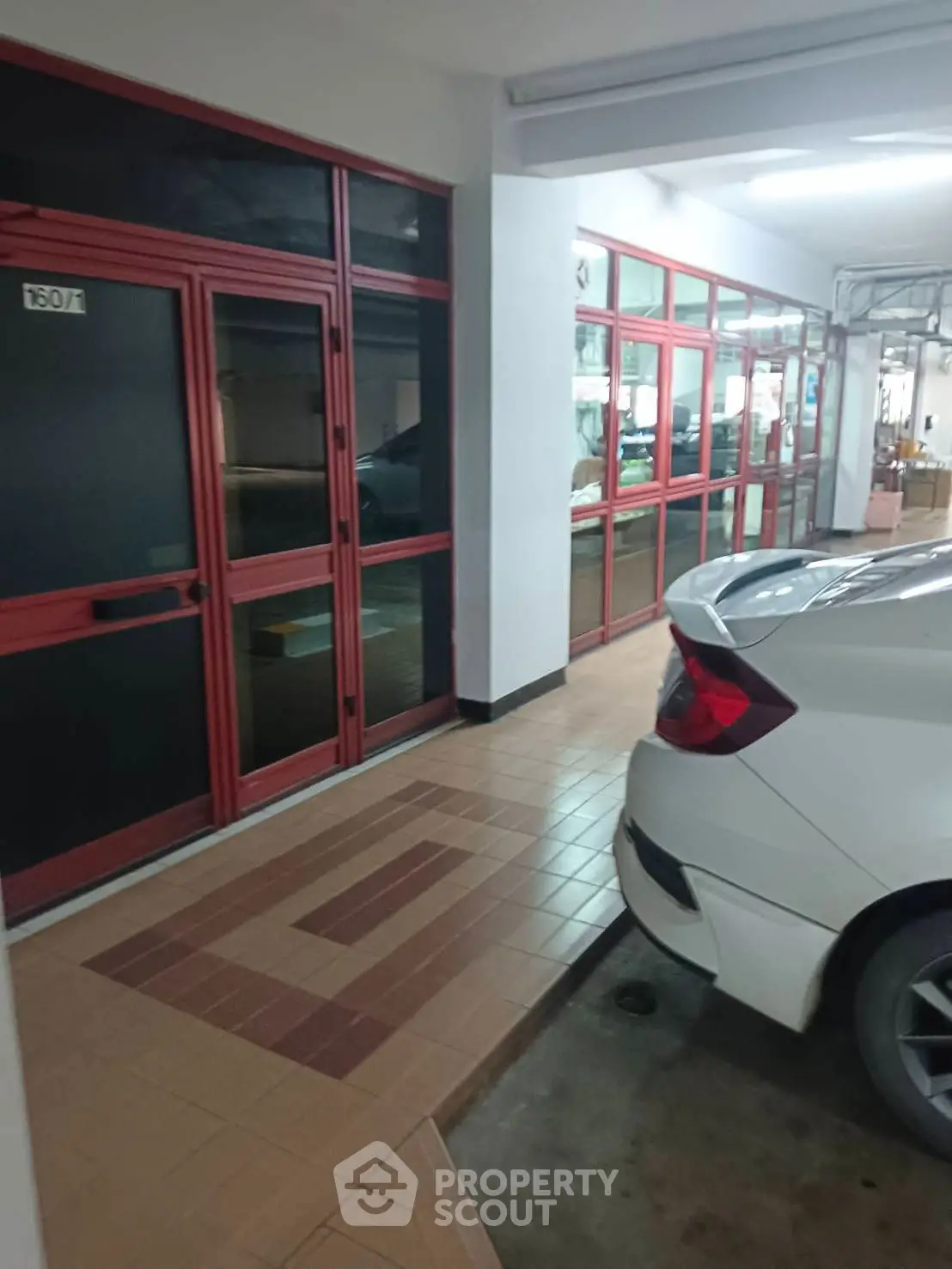 Covered parking area with tiled floor and adjacent glass doors