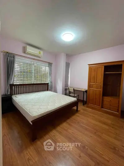 Spacious bedroom with wooden flooring and ample natural light