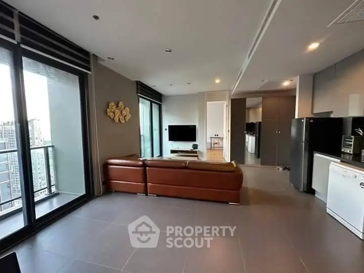 Spacious modern living room with open kitchen and balcony view in luxury apartment.