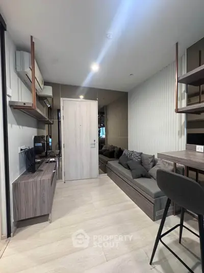 Modern living room with sleek furniture and neutral tones, featuring a cozy seating area and stylish shelving.