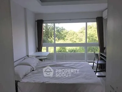 Bright bedroom with large window and serene green view