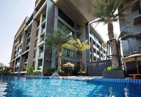 Luxurious modern apartment building with palm trees and inviting swimming pool.