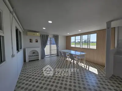 Spacious sunlit room with modern decor and large windows offering scenic views.