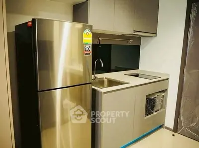 Modern compact kitchen with sleek cabinetry and stainless steel fridge
