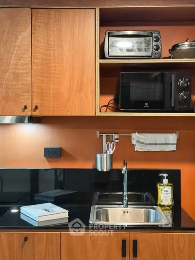 Modern kitchen with wooden cabinets, microwave, and sleek black countertop