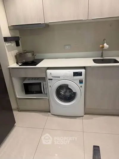 Modern kitchen with integrated washing machine and microwave, sleek cabinetry, and compact design.