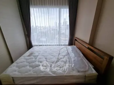 Spacious bedroom with large window offering city views, featuring a comfortable bed and elegant curtains.