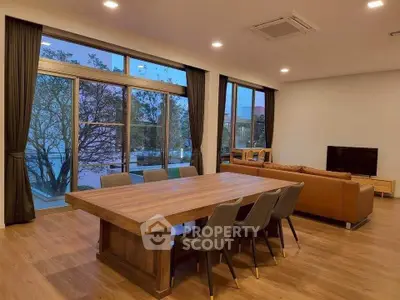 Spacious living room with large windows and elegant wooden dining table.
