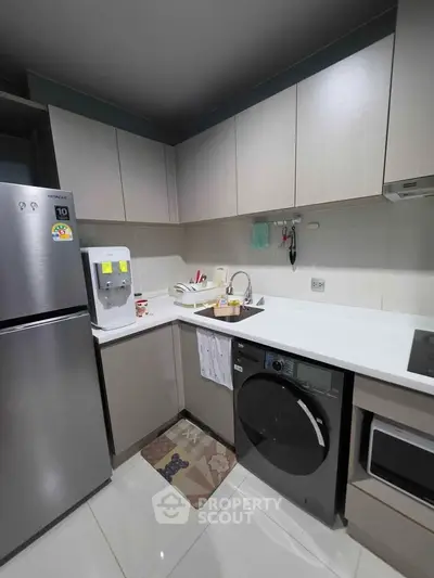 Modern kitchen with sleek cabinets, stainless steel fridge, and built-in appliances for efficient cooking.