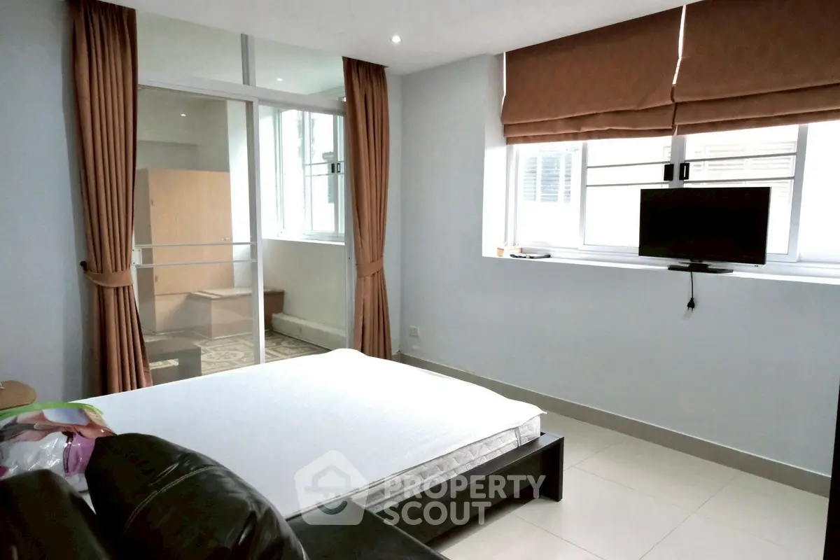 Spacious bedroom with modern decor and large windows for natural light.