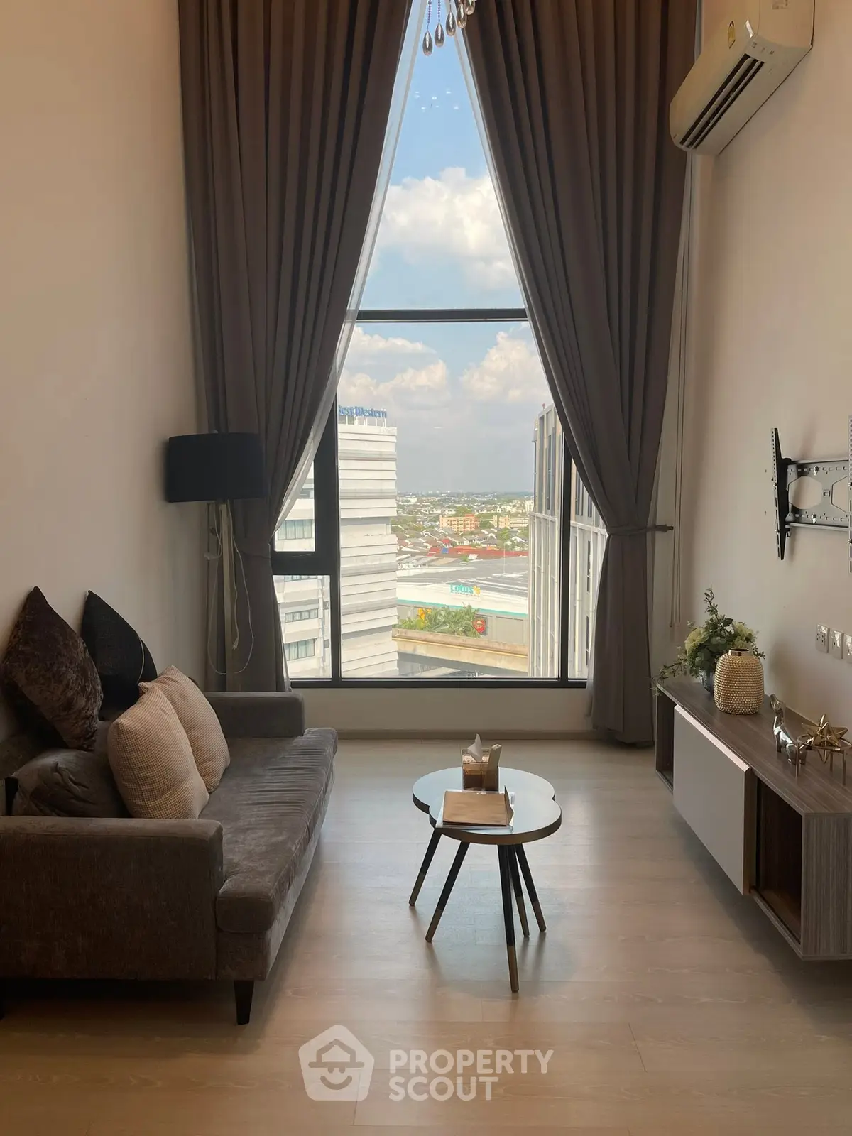 Modern living room with large window offering stunning city view, elegant decor, and cozy seating area.