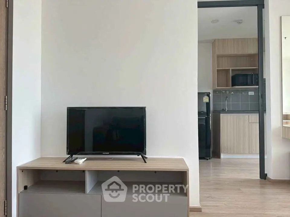 Modern apartment interior with sleek kitchen and cozy living area featuring a flat-screen TV.