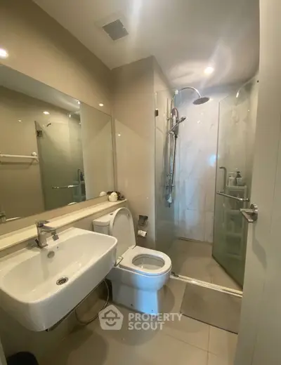 Modern bathroom with glass shower and sleek fixtures in contemporary apartment.
