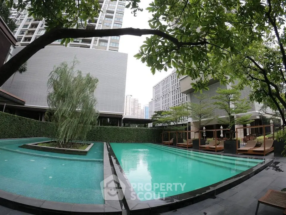 Luxurious outdoor pool area with modern design and lush greenery in a high-rise residential complex.