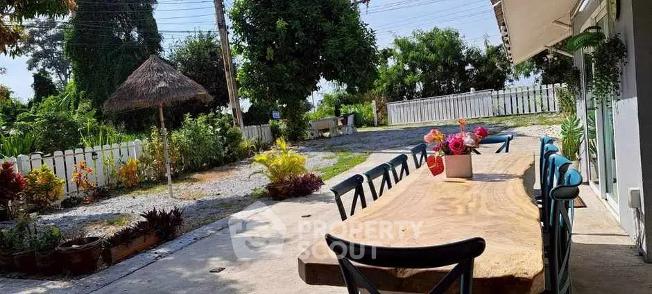 Charming outdoor patio with rustic wooden table and lush garden view.