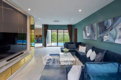Luxurious living room with modern decor and pool view, featuring plush blue sofas and elegant wall art.