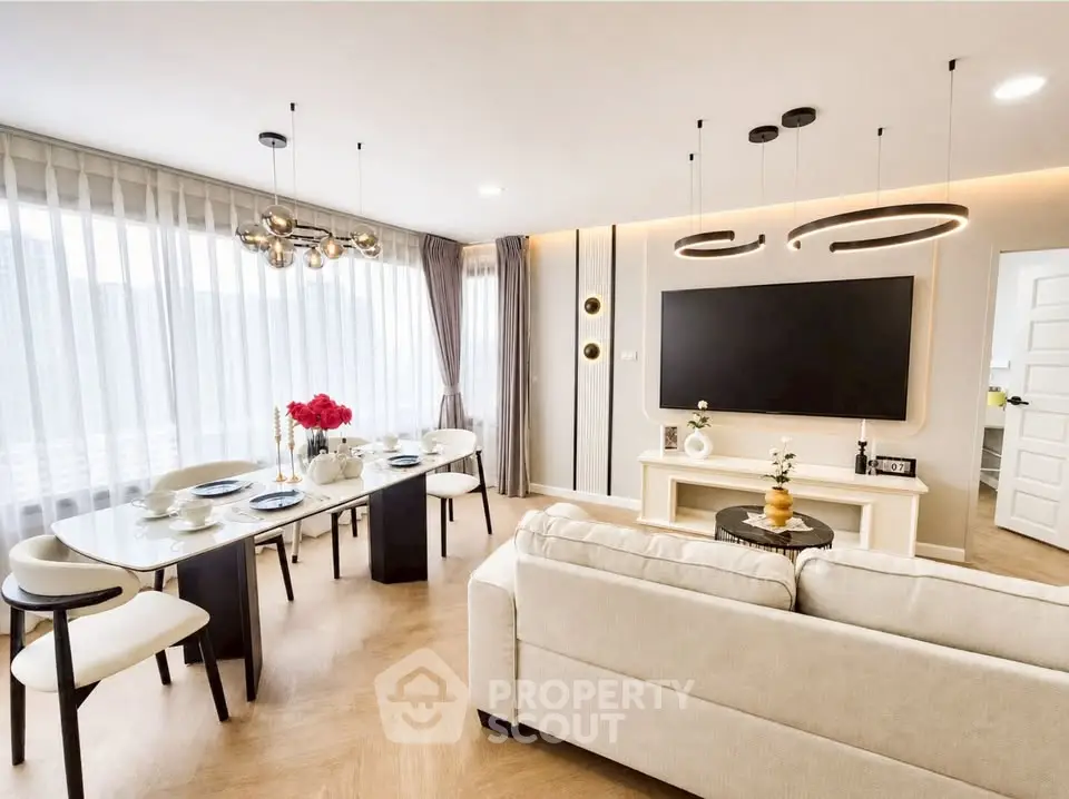 Elegant modern living room with dining area, featuring chic lighting and large windows.