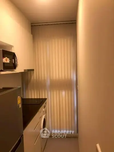 Compact kitchen with modern appliances and vertical blinds