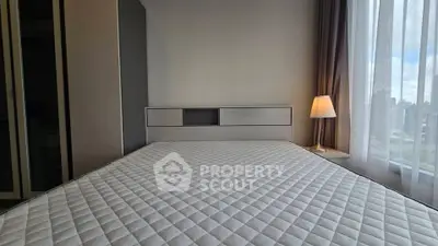 Modern bedroom with large window and stylish lamp, featuring a comfortable bed and sleek design.