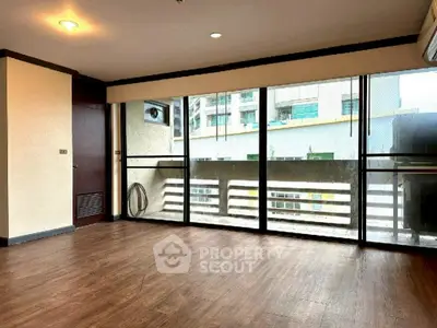 Spacious living room with large windows and wooden flooring in modern apartment.