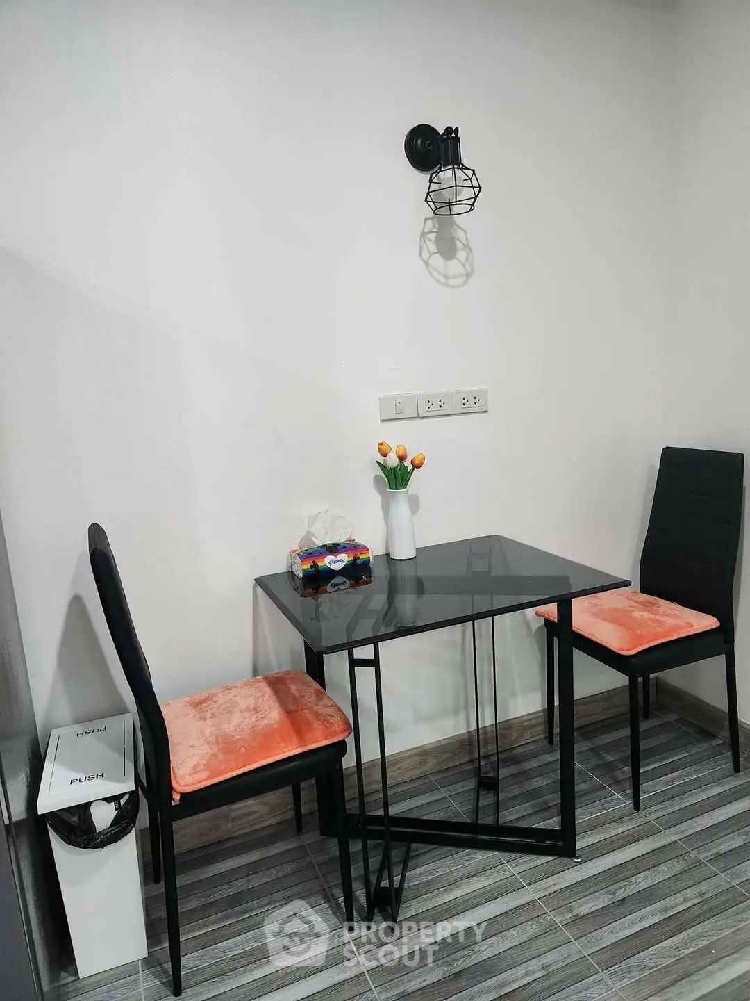 Modern dining nook with sleek glass table and stylish chairs in cozy apartment.
