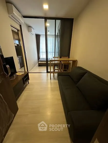 Modern living room with sleek furniture and glass partition leading to bedroom