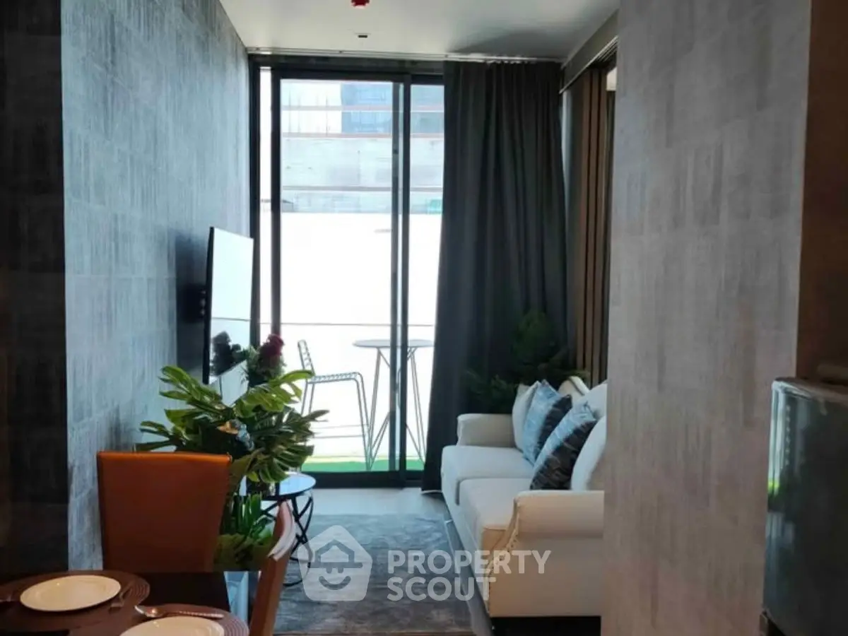Modern living room with balcony view, stylish furniture, and natural light.