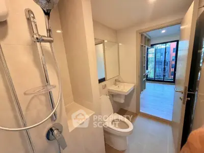 Modern bathroom with shower and toilet, leading to a bright room with balcony view.