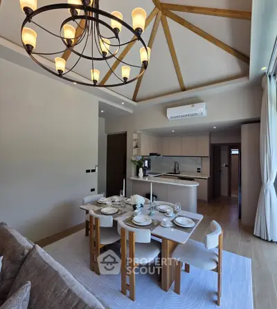 Elegant dining area with modern kitchen in open layout, featuring stylish chandelier and natural light.
