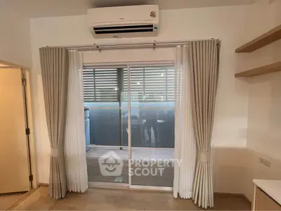 Modern living room with sliding glass doors and air conditioning, leading to a balcony.