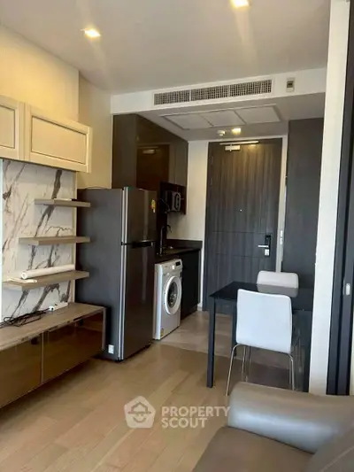 Modern apartment interior with kitchen and dining area, featuring sleek appliances and stylish decor.