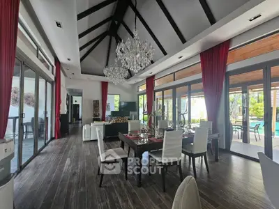 Luxurious open-plan living room with high ceilings, elegant chandelier, and pool view, perfect for entertaining.
