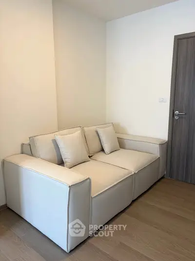 Cozy modern living room with plush beige sofa and wooden flooring, perfect for relaxation.