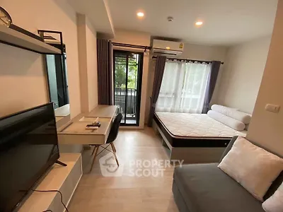 Modern studio apartment with cozy bed, desk, and balcony view.