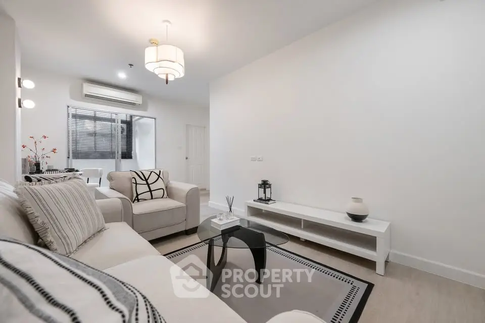 Modern living room with stylish decor and neutral tones, featuring a cozy sofa and elegant lighting.